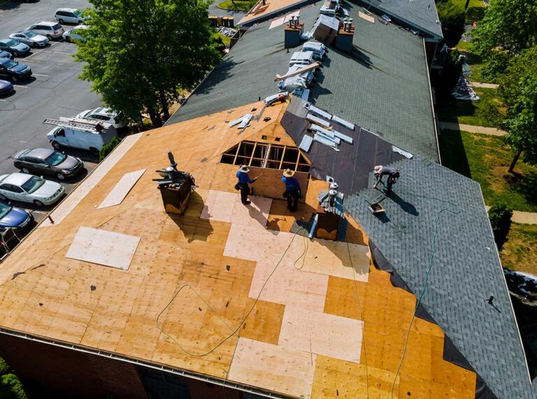 Homeowner inspecting roof gutters from the ground beside a snow-ready house
